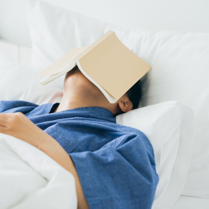 man fallen asleep with book on face